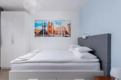 a white bedroom with a large bed with white pillows at Apartament Mateo in Kraków