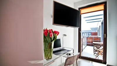 a vase of flowers on a table with a television at Apartament Mateo in Kraków
