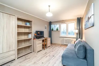 a living room with a blue couch and a desk at RentPlanet - Apartament Olsza in Kraków