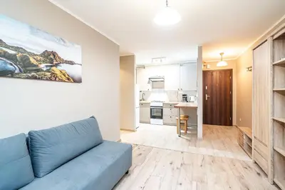 a living room with a blue couch and a kitchen at RentPlanet - Apartament Olsza in Kraków
