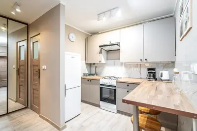a kitchen with white cabinets and a wooden counter top at RentPlanet - Apartament Olsza in Kraków