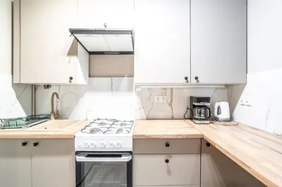 a kitchen with white cabinets and a stove top oven at RentPlanet - Apartament Olsza in Kraków
