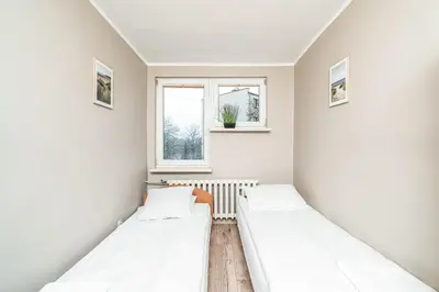 two beds in a white room with two windows at RentPlanet - Apartament Olsza in Kraków
