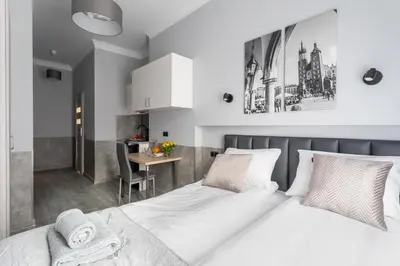 a bedroom with a white bed and a desk at SERENITY New Apartments Kraków in Kraków