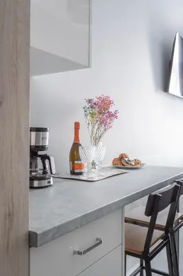 a kitchen counter with a bottle of wine and flowers at SERENITY New Apartments Kraków in Kraków