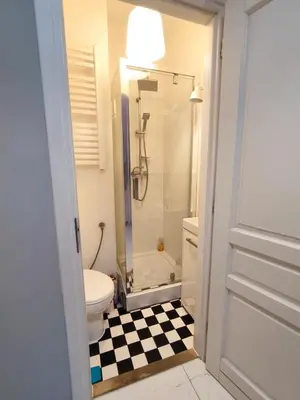 a bathroom with a shower and a toilet and a checkered floor at Daniel Apart Hotel Krakow in Kraków