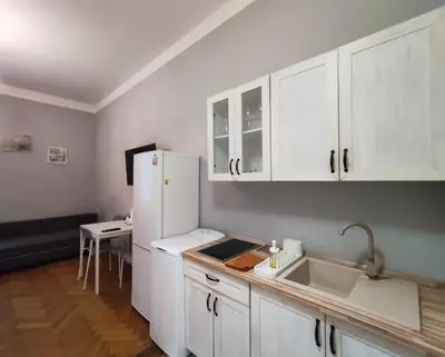a kitchen with white cabinets and a white refrigerator at Daniel Apart Hotel Krakow in Kraków