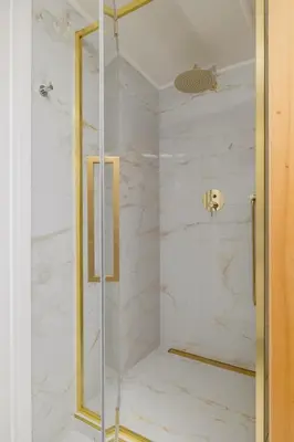 a shower with white marble walls and a glass door at 5 Bedroom apartment - Terrace, Jacuzzi, Sauna in Kraków