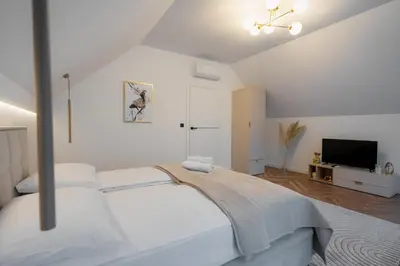 a white bedroom with a bed and a tv at Zamkowy Zakątek - Luksusowe domki z jacuzzi in Nowy Wiśnicz