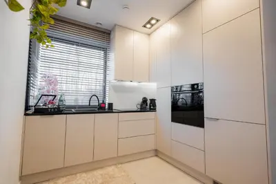 a kitchen with white cabinets and a window at Zamkowy Zakątek - Luksusowe domki z jacuzzi in Nowy Wiśnicz
