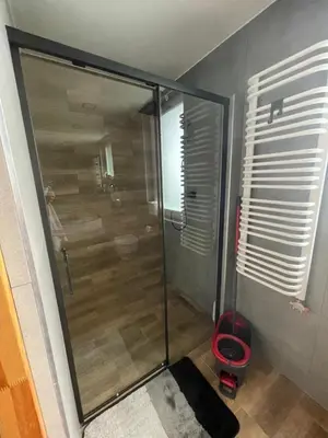 a shower with a glass door in a bathroom at Domki przy szlaku Szczebel in Lubień