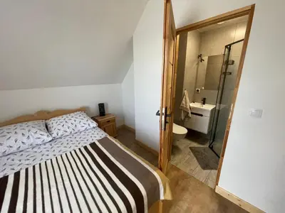 a bedroom with a bed and a bathroom with a shower at Domki przy szlaku Szczebel in Lubień