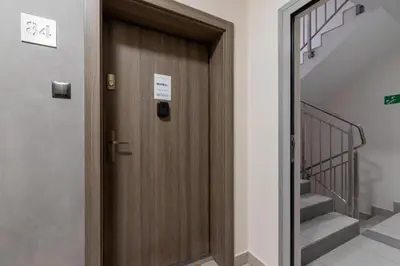 a wooden door in a hallway with stairs at Spacious Studio Zabłocie with Balcony Krakow in Kraków