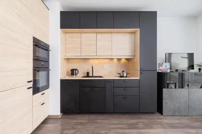 a kitchen with black cabinets and a sink at Spacious Studio Zabłocie with Balcony Krakow in Kraków