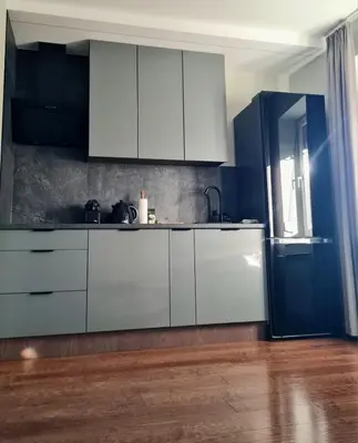 a kitchen with white cabinets and a blue wall at Home4You in Kraków