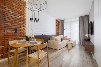 a living room with a table and a brick wall at Rakowicka Brick Apartment near Station by Noclegi Renters in Kraków