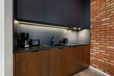 a kitchen with a sink and a brick wall at Rakowicka Brick Apartment near Station by Noclegi Renters in Kraków