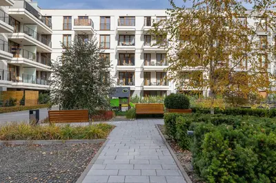 a building with two benches in a park at Rakowicka Brick Apartment near Station by Noclegi Renters in Kraków