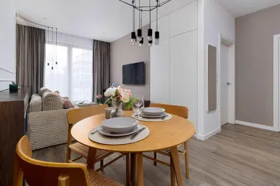 a dining room and living room with a table and chairs at Rakowicka Brick Apartment near Station by Noclegi Renters in Kraków