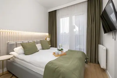 a bedroom with a bed with a television and a window at Stylish Apartment with Balcony near Krakow Old Town by Noclegi Renters in Kraków