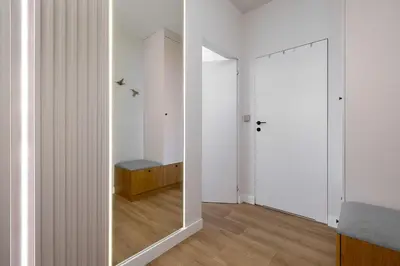 a hallway with a mirror and a room with white walls at Stylish Apartment with Balcony near Krakow Old Town by Noclegi Renters in Kraków