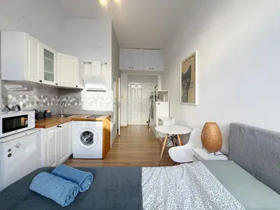 a kitchen and living room with white cabinets and a table at Pstrak zyblikiewicza in Kraków