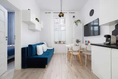 a living room with a blue couch and a kitchen at Charming One Bedroom Apartment in Krakow with a Perfect Location by Noclegi Renters in Kraków