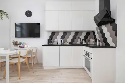 a kitchen with white cabinets and a table and a tv at Charming One Bedroom Apartment in Krakow with a Perfect Location by Noclegi Renters in Kraków