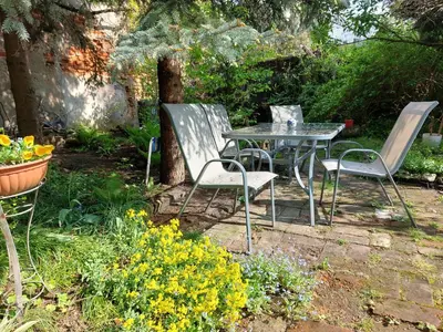 a table and chairs in a garden with flowers at Apartament Różana przy ICE in Kraków