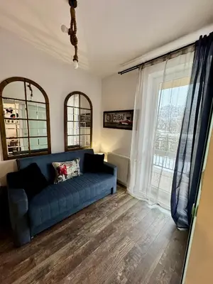 a living room with a blue couch and a window at LOFT Studio Wielicka in Kraków
