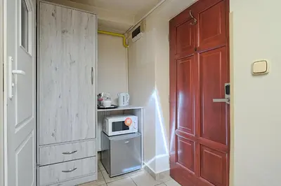 a small kitchen with a door and a microwave at Urban Nest - Double Room in the Attic in Kraków