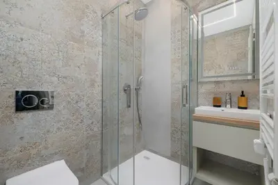 a bathroom with a glass shower and a sink at Studio apartment - Augustiańska 1 street in Kraków