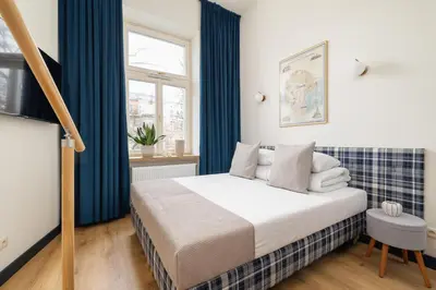 a bedroom with a bed with blue curtains at Studio apartment with mezzanine - Augustianska 1 in Kraków