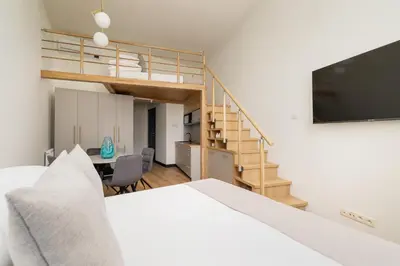 a bedroom with a white bed and a staircase at Studio apartment with mezzanine - Augustianska 1 in Kraków