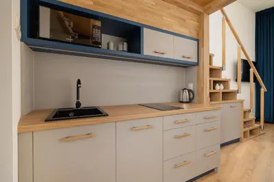a kitchen with white cabinets and a sink at Studio apartment with mezzanine - Augustianska 1 in Kraków