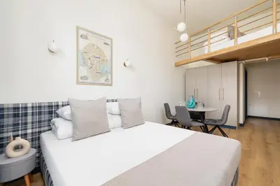 a bedroom with a large white bed and a table at Cozy studio - Augustiańska 1 street in Kraków