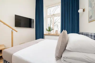 a bedroom with a bed with blue curtains and a window at Cozy studio - Augustiańska 1 street in Kraków