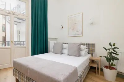 a bedroom with a bed with green curtains and a plant at Studio - Augustiańska 1 in Kraków