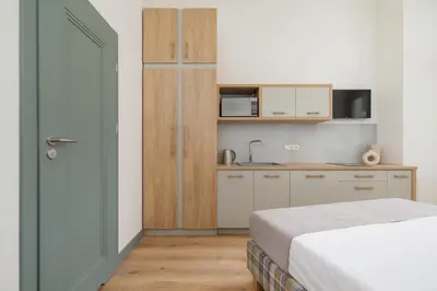 a bedroom with a bed and a small kitchen at Studio - Augustiańska 1 in Kraków