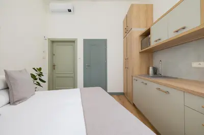 a bedroom with a white bed and a kitchen at Studio - Augustiańska 1 in Kraków