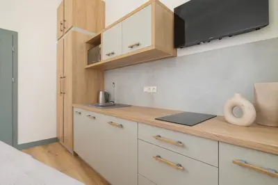 a kitchen with white cabinets and a wooden counter top at Studio - Augustiańska 1 in Kraków