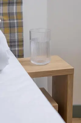 a glass on a wooden table next to a bed at Studio - Augustiańska 1 in Kraków