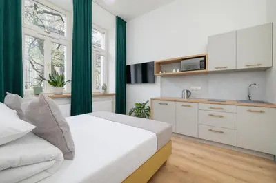 a bedroom with a white bed and a kitchen at Studio - Augustiańska 1 - Kazimierz in Kraków