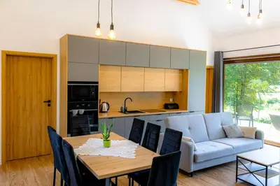 a kitchen and living room with a table and a couch at Domki nad potokiem in Lipnica Murowana