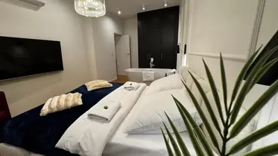 a bedroom with a white bed with a plant at Wawel Love & Bath Apartment in Kraków