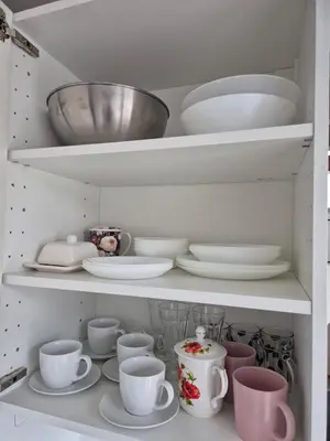a white cabinet filled with dishes and cups and plates at The Hidden Echo Studio Kazimierz, #Netflix # AC# in Kraków