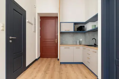 a kitchen with white cabinets and a red door at 1-bedroom apartment - Augustiańska 1 street in Kraków