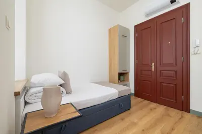 a small bedroom with a bed and a red door at Cozy studio - Augustiańska 1 street in Kraków