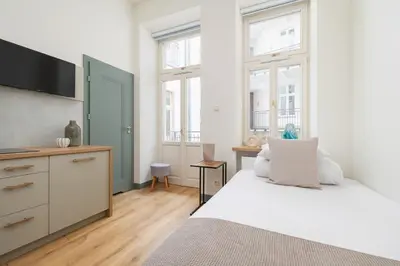 a bedroom with a white bed and a tv at Cozy studio - Augustiańska 1 street in Kraków