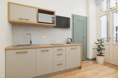 a kitchen with white cabinets and a sink at Cozy studio - Augustiańska 1 street in Kraków